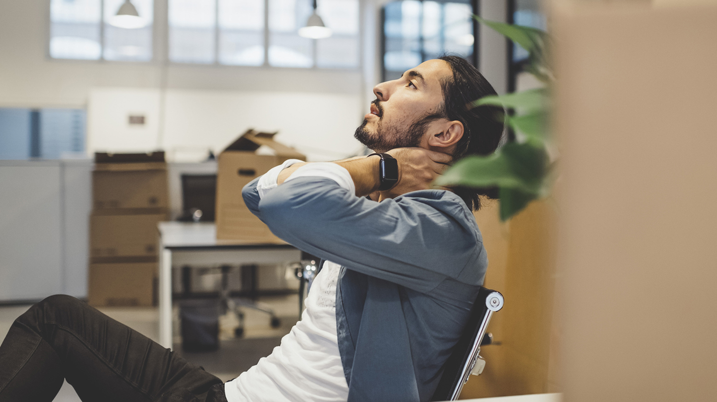 Verspannung im Nacken: Wieder locker werden Die Verspannung im Nacken massiert sich ein junger Mann, der auf einem Bürostuhl sitzt, einfach weg